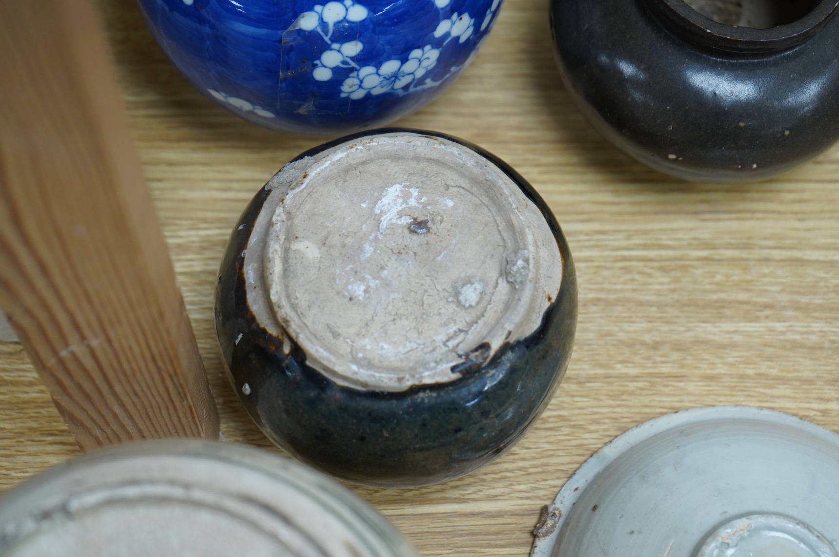 A collection of Chinese pottery jars and a decorated plate, tallest jar 18cm high